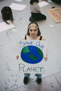 High angle view of female protector holding poster for environmental issues