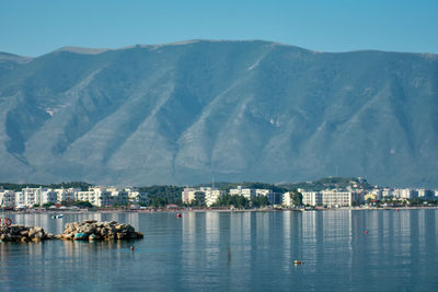 Scenic view of sea by city buildings against sky