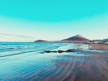 Scenic view of beach against clear blue sky