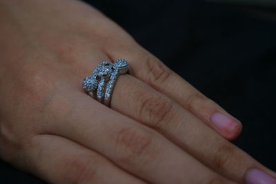 Close-up of woman showing ring against black background