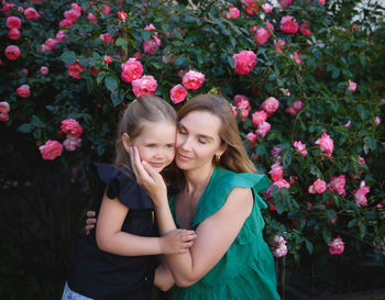 Portrait of smiling woman with pink flowers against plants