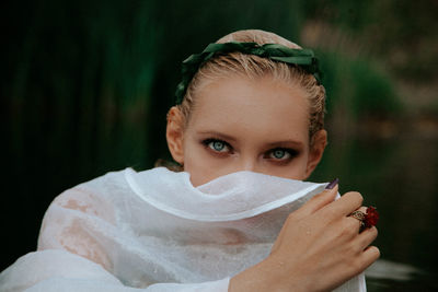 Close-up portrait of beautiful woman covering face with scarf