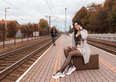 Full length of woman sitting on railroad station platform