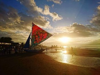 People on beach against sky during sunset