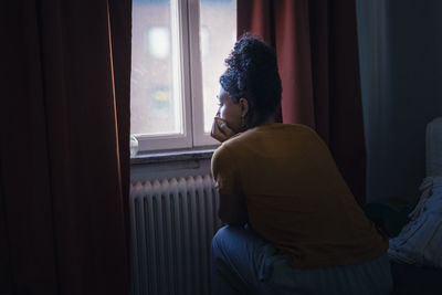 Pensive young woman sitting at home