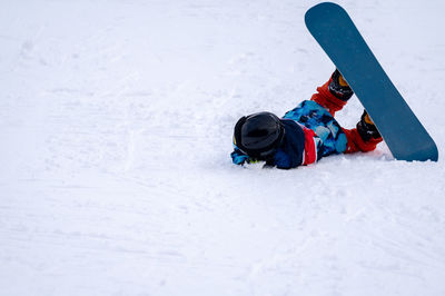 Person with snowboard on the snow. one asian child is falling on the ground. winter sport.