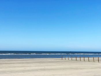 Scenic view of beach against clear blue sky