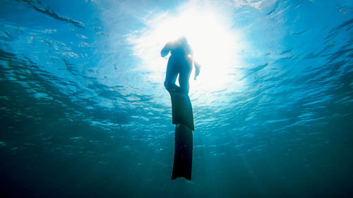 Low angle view of silhouette boy swimming in sea