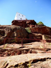 Low angle view of built structure on rock against sky