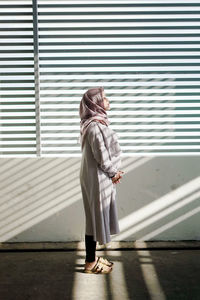 Full length of woman standing against wall