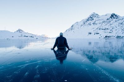 Rear view of woman on snowcapped mountain against clear sky