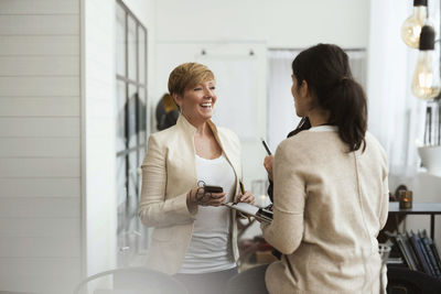Happy businesswomen talking while standing in office