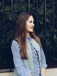 Young woman standing against tree