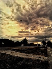 Road by trees against sky during sunset