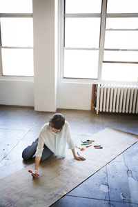 High angle view of businesswoman preparing chart while sitting on floor