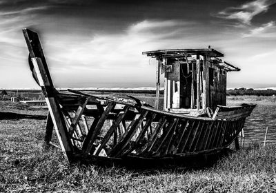 Abandoned boat on field against sky