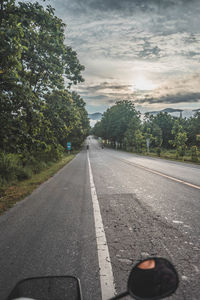 Road by trees against sky