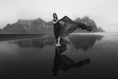 Lady with long chiffon cape on sea beach monochrome scenic photography