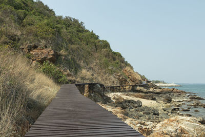 Walkway leading towards sea against clear sky