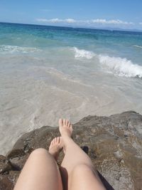 Low section of person on beach against sea