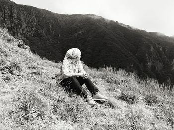 Woman sitting on land against mountain