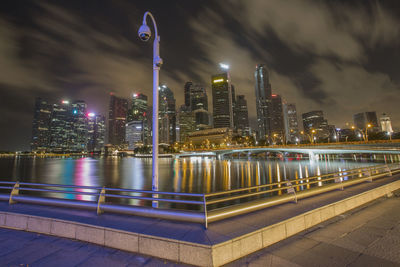 Illuminated modern buildings in city against sky at night