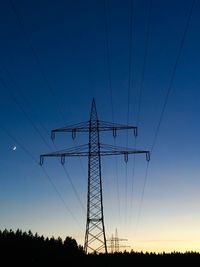 Silhouette electricity pylons against clear sky at dusk