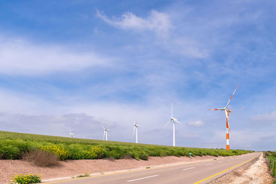 Wind turbines on field against sky