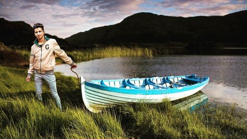 Man standing by boat in lake against sky