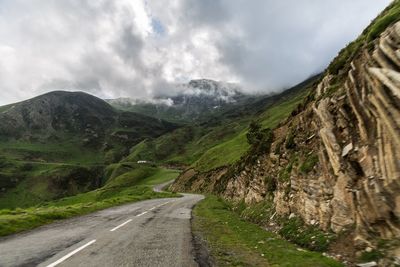 Road amidst mountains against cloudy sky