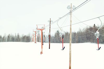 Ski lift hanging on snow field against clear sky