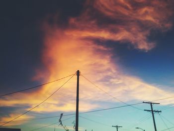 Low angle view of electricity pylon against cloudy sky