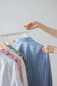 A woman's hand holds a hanger with clothes in the wardrobe. recycling. stylist or merchandiser