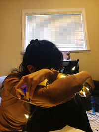 Rear view of woman holding window at home