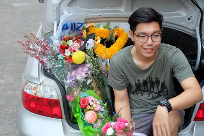 Smiling young man selling bouquets in car trunk