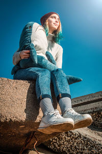 Low angle view of smiling woman sitting against sky