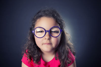 Close-up portrait of girl wearing eyeglasses against black background