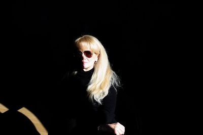Senior woman wearing sunglasses while standing in darkroom