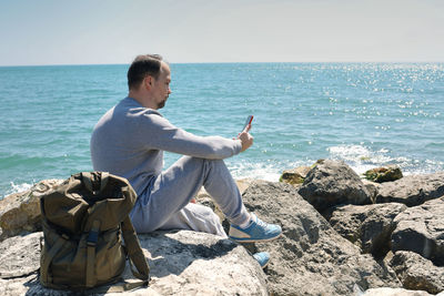 Man sitting on rock at beach