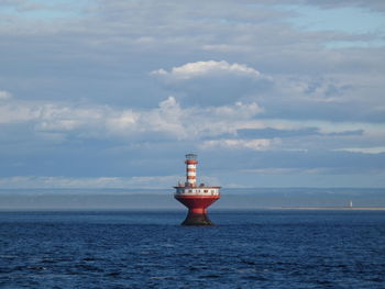 Lighthouse by sea against sky