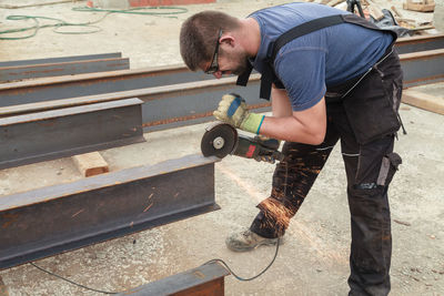 Side view of welder cutting metal with electric saw