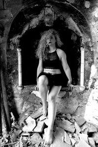 Full length of woman sitting in abandoned building