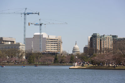 Buildings by river against sky in city