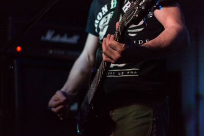 Midsection of man playing guitar