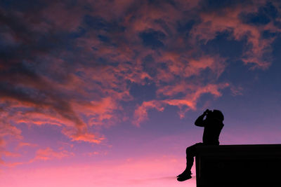 Low angle view of silhouette man standing against orange sky