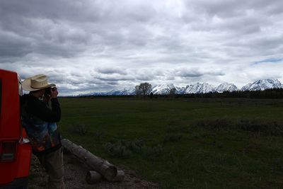 Man photographing landscape against cloudy sky