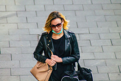 Young woman wearing sunglasses against brick wall