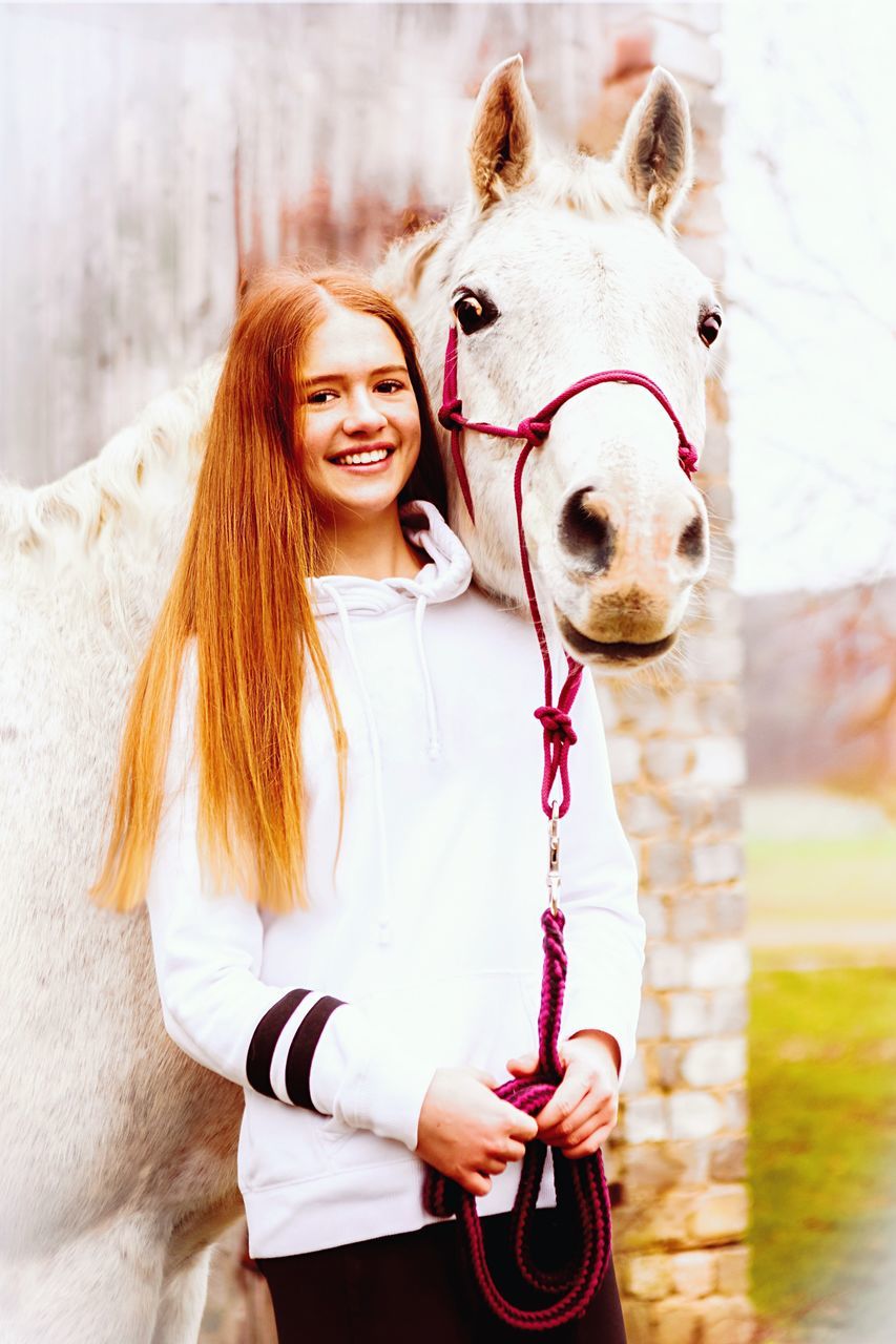 PORTRAIT OF YOUNG WOMAN WITH HORSE IN A MOUTH