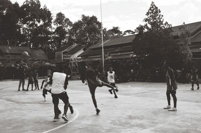 Group of people playing soccer against sky