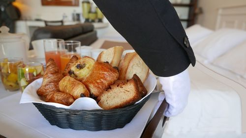 Cropped image of waiter holding breakfast in bedroom